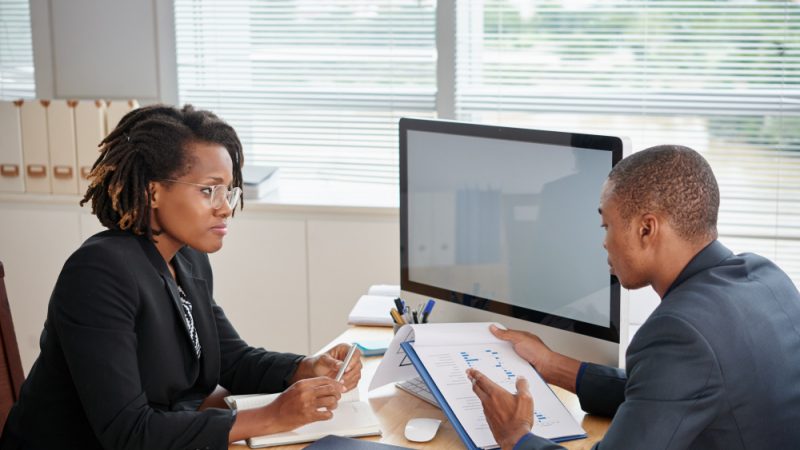 afro-american-man-suit-holding-documents-talking-female-boss